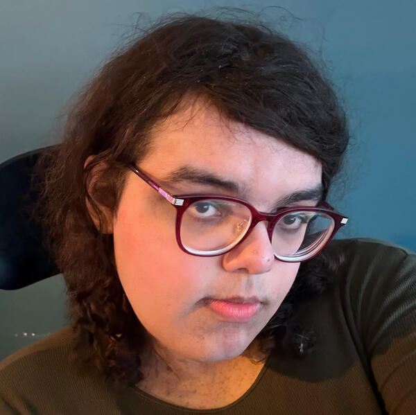 Hicup PFP Hicup is wearing a green dress and sitting in front of a green wall, she has makeup on including blusher and she is smiling